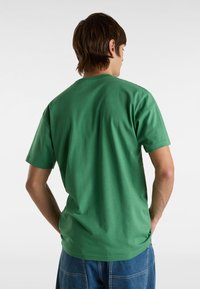 Camiseta de algodón de manga corta en verde, con cuello redondo y un corte relax, con una textura suave y sin patrones ni logotipos visibles.