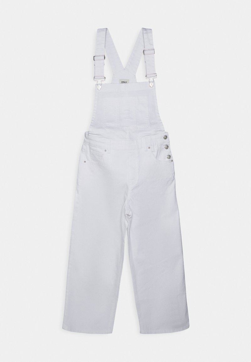 Bílé džínové kšandy s nastavitelnými křížovými popruhy, přední kapsou na hrudi, bočními knoflíky a širokými nohavicemi na jednobarevném bílém pozadí.