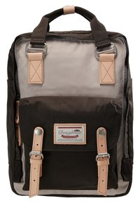 Sac à dos rectangulaire bicolore en tissu avec poche avant à rabat, bretelles et poignée en cuir beige, et une étiquette rectangulaire de la marque Doughnut sur la poche.