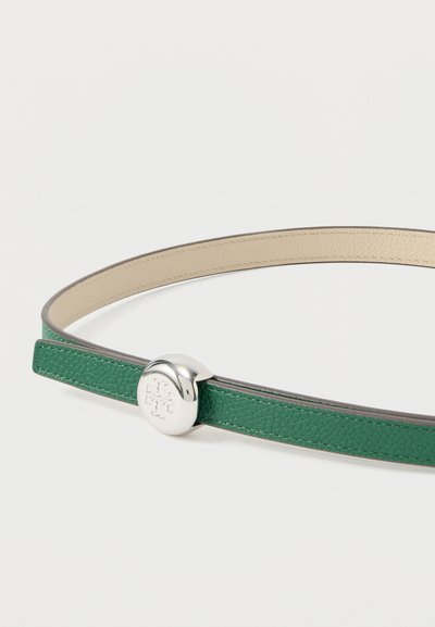 Λεπτή πράσινη δερμάτινη ζώνη με μπεζ εσωτερική επένδυση, που διαθέτει στρογγυλή ασημένια πόρπη με ανάγλυφο διακοσμητικό λογότυπο.