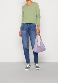 Maglietta verde chiaro a maniche lunghe con texture, jeans blu a vestibilità slim, sneakers in suede verdi e una borsa a tracolla viola con texture. Design semplice, outfit casual.