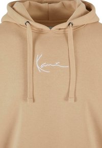 Hoodie beige realizzata in morbido tessuto, con cappuccio regolabile tramite coulisse, occhielli in metallo e logo bianco ricamato sul davanti.