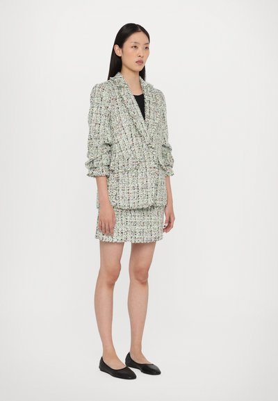 Tweed-Blazer und Minirock-Set mit einer mehrfarbigen Textur, ausgestattet mit einem Reverskragen, voluminösen Ärmeln und schwarzen Ballerinas.
