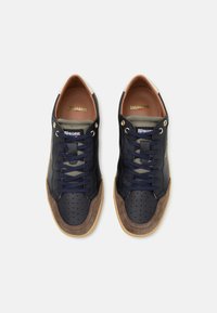 Sneakers in pelle e camoscio blu navy con dettagli perforati, accenti marroni e lacci blu. Presentano un linguetta sul tallone color crema e una soletta color nocciola.
