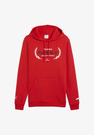 Sweatshirt rouge avec une capuche, une poche avant et un texte blanc portant "75 ans de Formule 1" ainsi que des graphiques de lauriers décoratifs. Logo Puma sur la manche.