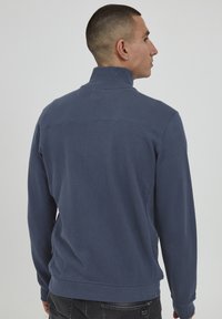 Sudadera de color azul marino con un cuello alto, puños acanalados y dobladillo. Fabricada con un tejido texturizado, con un detalle de panel cosido en la parte posterior.
