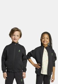 Giubbotti a zip neri con accenti verdi, realizzati in tessuto morbido, dotati di tasche laterali e polsini a costine. Stilizzati per bambini.