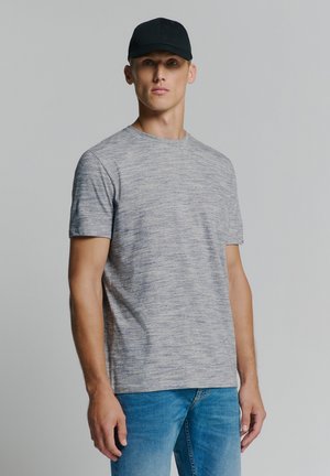 Graues Heather T-Shirt mit kurzen Ärmeln und rundem Ausschnitt, kombiniert mit blauen Jeans und einer schwarzen Kappe. Glatte Textur, lässige Passform.