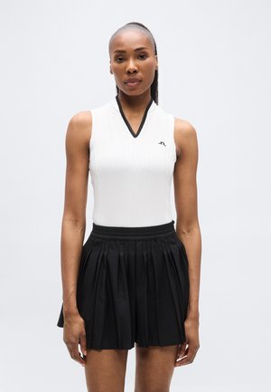 Valge triibuline varrukateta topp musta V-kaelusega, sobitatud musta voltseelikuga, millel on elastne vöökoht.