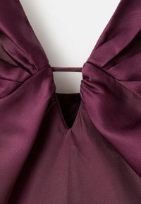 Tessuto in satin bordeaux con scollatura strutturata caratterizzata da pieghe. Il design include un'apertura a chiave al centro.