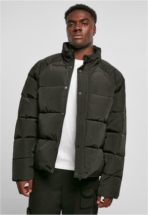 Black puffer jacket with a high collar, snap and zip closure, featuring boxy quilted sections and a matte texture.