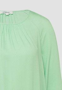 Blouse à manches longues vert menthe avec encolure ronde, détails de tissu froncé et étiquette de la marque s.Oliver au niveau du col.