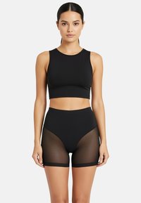 Top corto sportivo nero con scollo tondo e pantaloni corti in vita alta abbinati, dotati di pannelli laterali in mesh trasparente. Tessuto morbido e elasticizzato.