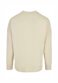 Langarmshirt aus cremefarbigem Baumwollstoff mit Rundhalsausschnitt, lockerer Passform und robusten Bündchen. Glatte Textur mit minimaler Verzierung.