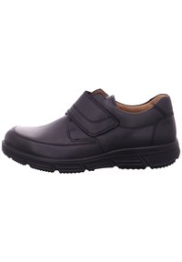 Black leather shoe with a velcro strap, rounded toe, and rubber outsole featuring treaded pattern for grip. Minimal design details.
