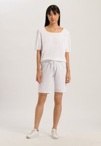 Top bianco a maniche corte con scollatura quadrata, abbinato a pantaloni corti con coulisse coordinati. L'outfit presenta una texture morbida e una vestabilità rilassata.