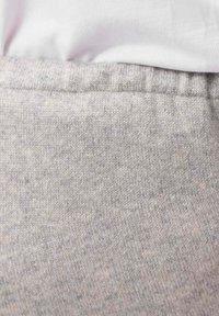 Grå stickad tyg med subtila variationer i färg och struktur, med en mjuk midjeresår upptill. Den nedre delen är slät och jämn.