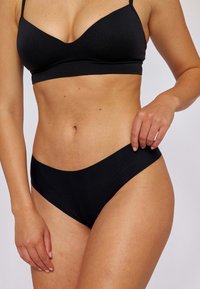 Zwarte bralette en high-waisted bikini. Zacht, rekbaar materiaal met een gladde textuur. Minimalistisch ontwerp, naadloze randen en geen zichtbare hardware.