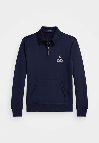 Sweater azul-marinho com fecho de meia zip, feito de material macio, apresentando um bolso frontal e um logo bordado no lado esquerdo do peito para detalhes.