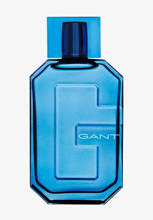 Blaues Glasflasche in achteckiger Form mit einem quadratischen Deckel. Auf der Flasche befindet sich ein auffälliges erhabenes „G“ und der Markenname „GANT“ in Weiß.