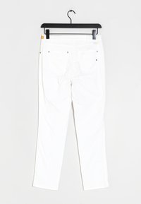 Pantaloni bianchi in cotone appesi a una gruccia nera. Presentano due tasche posteriori, rivetti in metallo e una texture liscia con un design a gamba dritta.