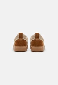 Chaussures en suede marron et tissu tricoté avec une semelle en caoutchouc, présentant un dos bas et une languette de tirage. Design simple avec un dessus texturé.