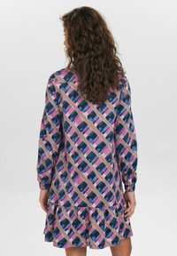 Abito a maniche lunghe con un motivo a strisce diagonali in rosa, blu e verde su uno sfondo beige chiaro. Dettaglio di orlo arricciato.