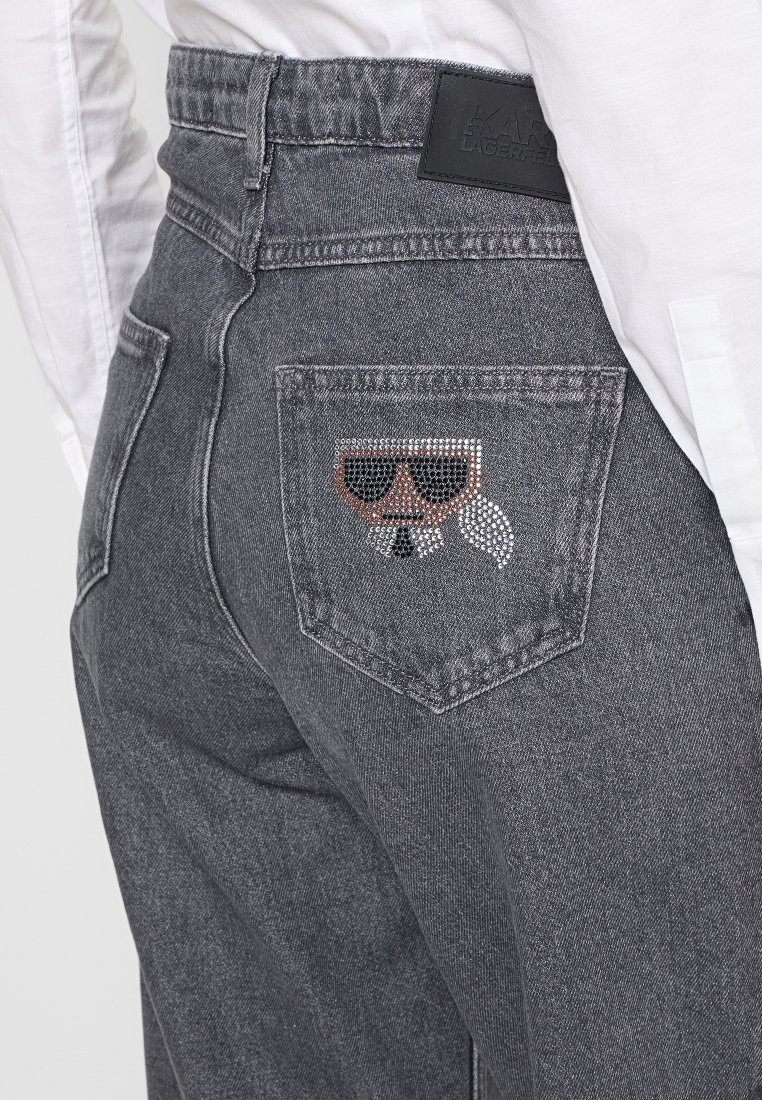 Jeans in denim grigio con una tasca posteriore decorata con un design di un volto con occhiali da sole e cravatta, impreziosita da paillettes.