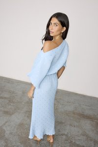 Lyseblå off-shoulder kjole med plisserte detaljer og spredte metalliske aksenter. Har en tettsittende silhuett og en flytende bunn.
