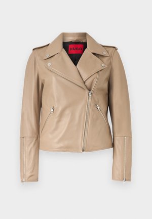 Bēša ādas motobraucēja jaka ar sudraba rāvējslēdzējiem priekšējās kabatās, piedurknēs un asimetriskā priekšējā aizdarei, ar plašu atloku apkakli.