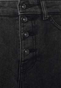 Svarta denim jeans med hög midja som har en knäppning med fyra svarta knappar, kraftig sömnad och en lätt textur.