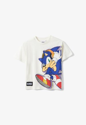 Camiseta blanca de manga corta con Sonic the Hedgehog usando auriculares y zapatos rojos, con un pequeño parche con el logo de "Sonic the Hedgehog".