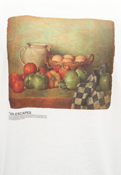 Καλάθι με αυγά, κεραμικό κανάτι, διάφορες ντομάτες και πράσινα μήλα, και ένα ασπρόμαυρο καρό ύφασμα πάνω σε ξύλινο τραπέζι.