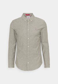 Green button-up shirt with long sleeves, collared design, and small logo on the chest. Soft texture and rounded hemline.