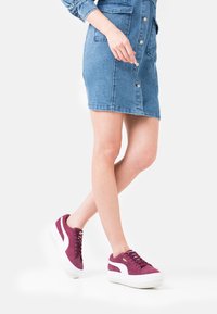 Maroon mockaskor med vita detaljer, rund tå och texturerad sula. Matchas med en jeansklänning med knappar och fickor.