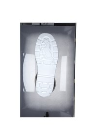 Semelle de chaussure en caoutchouc blanc avec un motif de grip texturé. Présente un logo de licorne en relief et la marque "MUSTANG". L'arrière-plan est gris et réfléchissant.