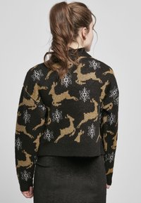 Black knitted sweater featuring a reindeer pattern in gold and white, with a cropped design and textured fabric.