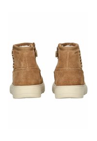 Bottines en suède marron avec une finition texturée, dotées d'une semelle en caoutchouc blanc et d'une doublure en mesh, affichant des détails de lacets sur le côté et un logo.