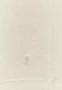 Jasno-beżowy materiał o gładkiej fakturze, z małym haftowanym logo w dopasowanym kolorze. Szczegóły przeszycia na dolnym wykończeniu.