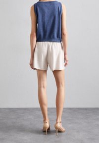 Námořnický bezrukávový top s volným střihem, doplněný světle zbarvenými texturovanými šortkami. Poznámka: béžové sandály na podpatku s pásky. Jednoduchý design bez viditelných vzorů.