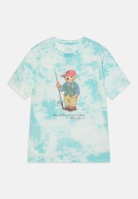 Camiseta de algodón con un patrón de teñido anudado en azul claro, que presenta un gráfico de un oso vestido de pescador sosteniendo una caña de pescar.