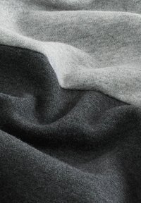 Tejido gris y gris oscuro con una superficie suave y texturizada, que muestra una mezcla suave de colores en un diseño abstracto y estratificado.