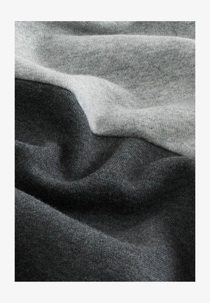 Un tissu gris et gris foncé avec une surface douce et texturée, présentant un mélange homogène de couleurs dans un design abstrait et superposé.