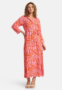 Abito maxi con maniche lunghe, caratterizzato da un audace motivo a strisce zebra in rosa e arancione, con chiusura a bottoni frontale e cintura coordinata in vita.