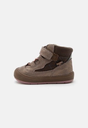 Chaussure haute pour enfant marron avec bride velcro, panneaux latéraux en mesh et semelle en caoutchouc avec rainures roses.