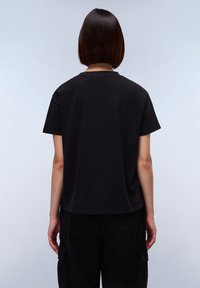 Černé bavlněné tričko s volným střihem, krátkými rukávy a kulatým výstřihem, s hladkou strukturou a jednoduchým designem.