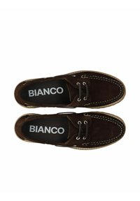 Pruun nahast paadijalatsid valgete õmblustega, nöörimisega disain ja must siseriie, millel on trükitud "BIANCO." Klassikaline ümar nina kuju.