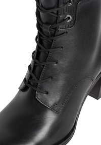 Bottine en cuir noir avec lacets sur le devant, détails cousus, panneau texturé et talon bloc.