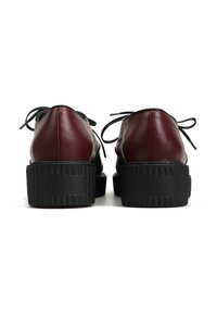 Burgundowe skórzane buty z czarną gumową podeszwą, posiadające okrągły czubek, sznurowany fason oraz teksturowane obcasy dla lepszej przyczepności.
