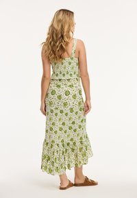Tweedelige jurk met bloemdecor in groen en wit, met een smocked lijfje, vierkante schouderbandjes en een ruffles aan de onderkant van de rok.